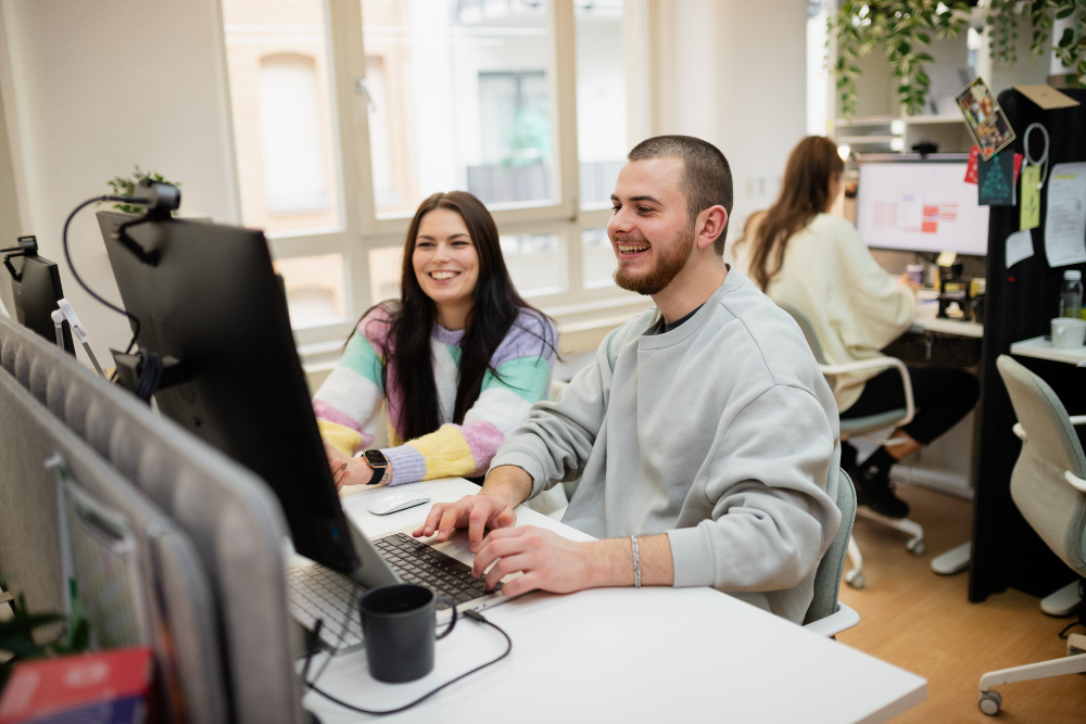 Zwei Personen die zusammen am Computer arbeiten