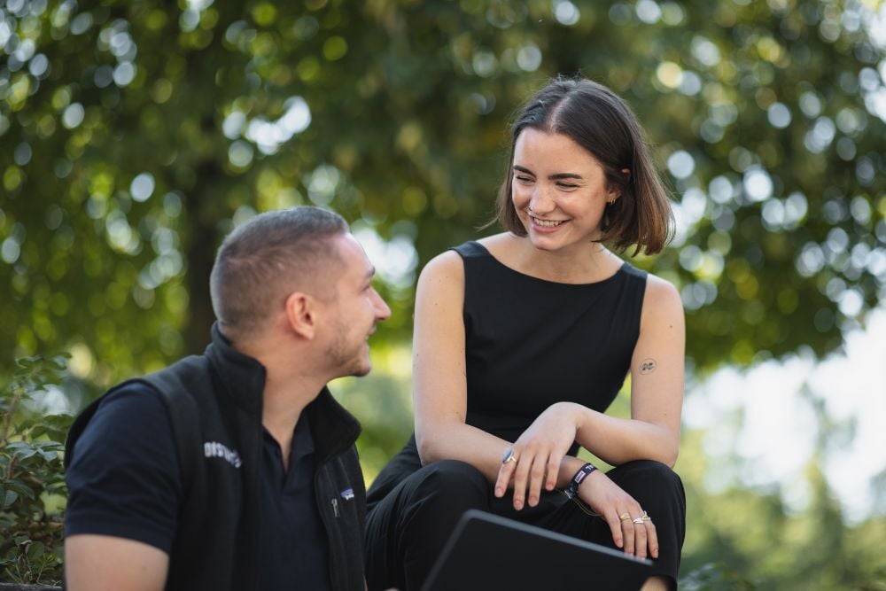 Zwei Personen die zusammen am Laptop arbeiten und sich anschauen